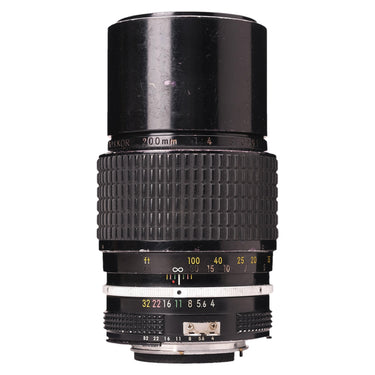Nikon 200mm f4 AI Nikkor lens standing upright showing barrel engraving, serial number, and aperture ring