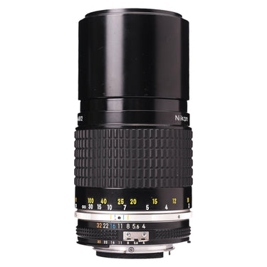 Nikon 200mm f4 AI-S Nikkor lens standing upright with built-in hood extended and distance scale
