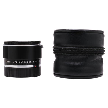 Leica APO-Extender-R 2x beside a black leather zip storage case